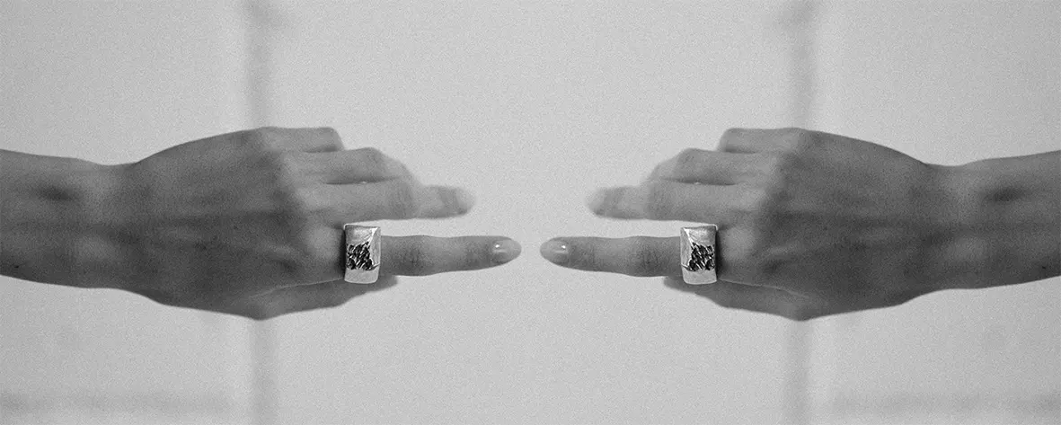 Two hands reaching towards each other, each wearing a Born of Chaos ring