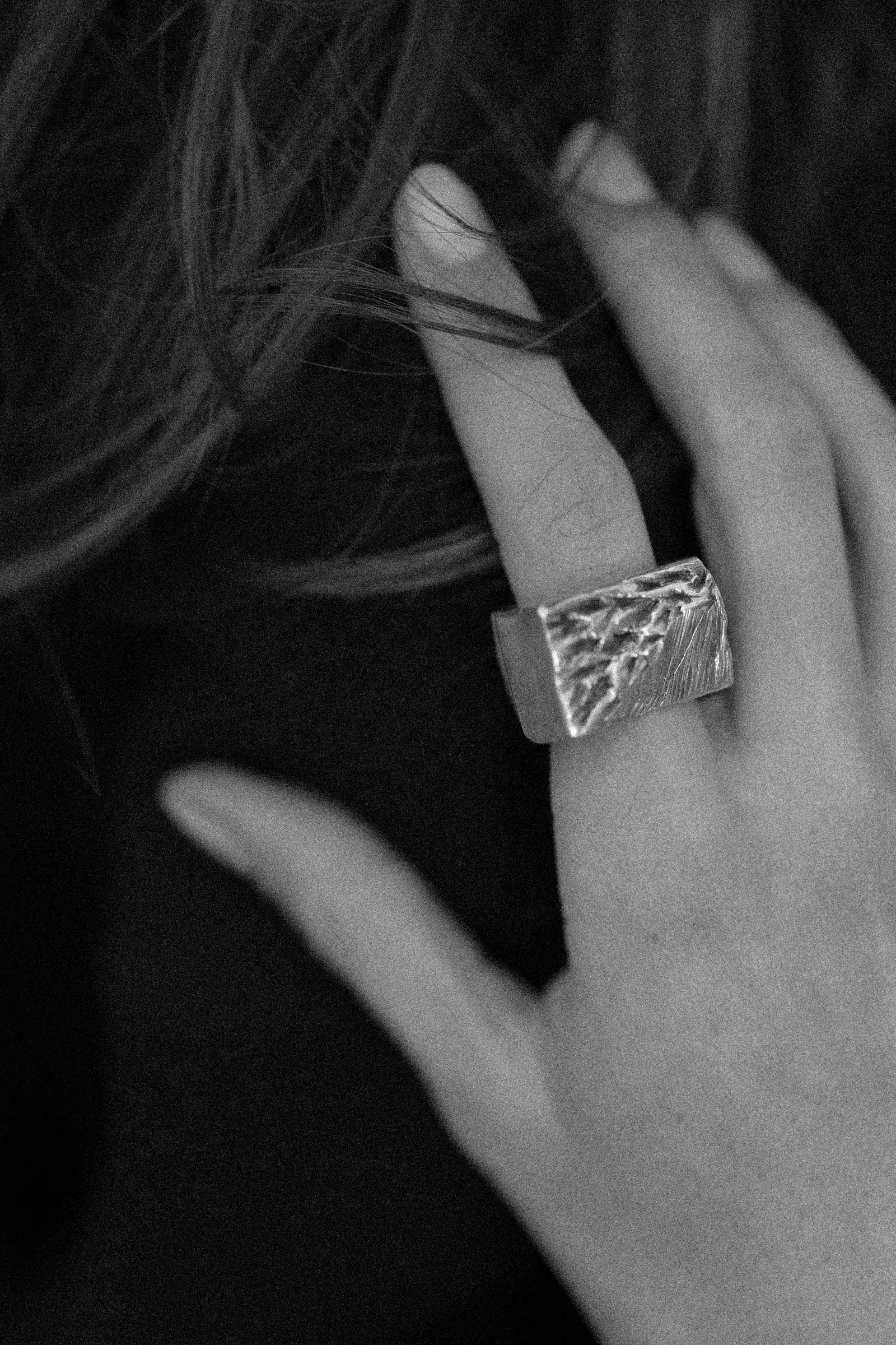 Born of Chaos ring worn on a hand, in black and white