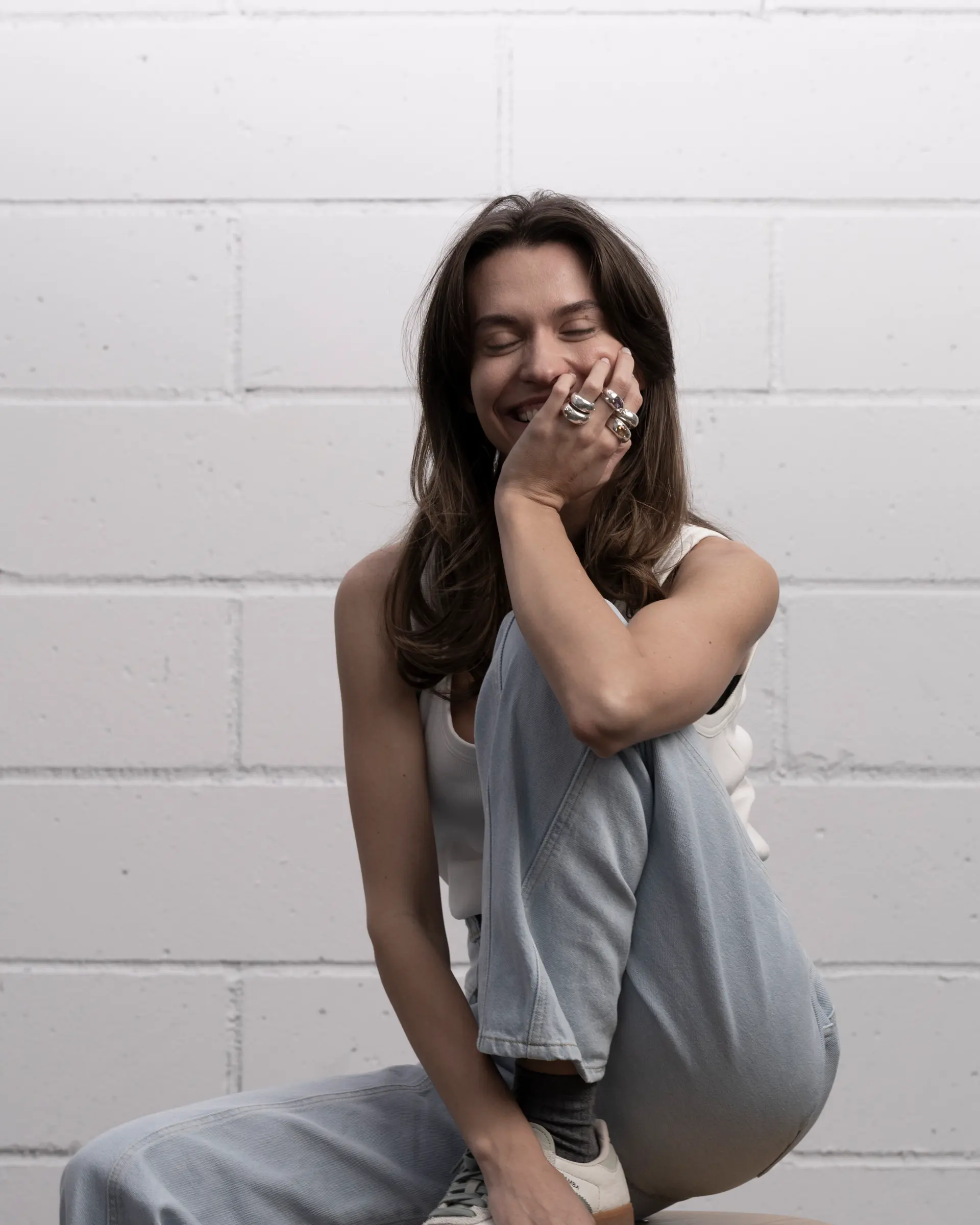 Seated portrait, hands stacked with rings